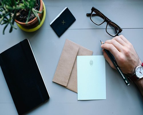 A clean envelope envelope sitting on a minimal desk surface next to a pen