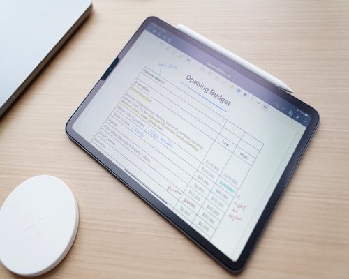 A tablet showing a document layout placed on a neat wooden desk under diffuse room lighting
